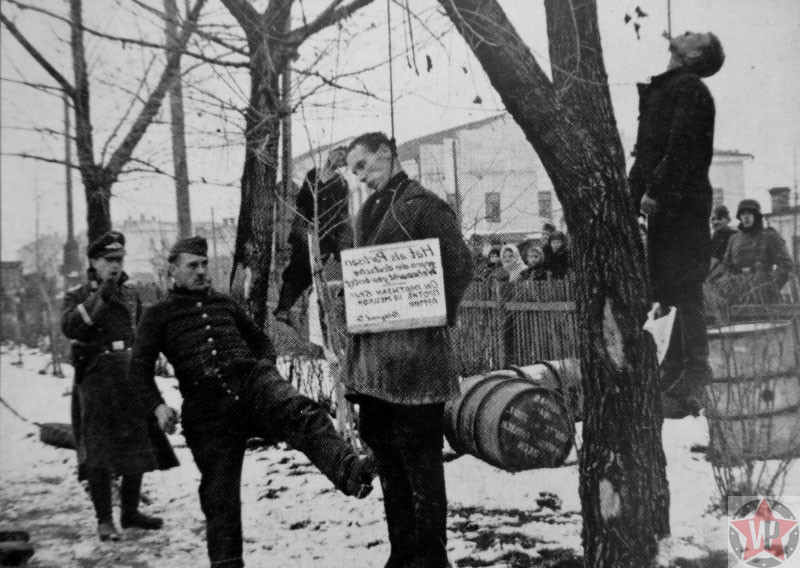 Солдат Вермахта пинает тело повешенного Советского партизана 